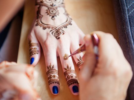 Drawing mehndi on the hand of a girl