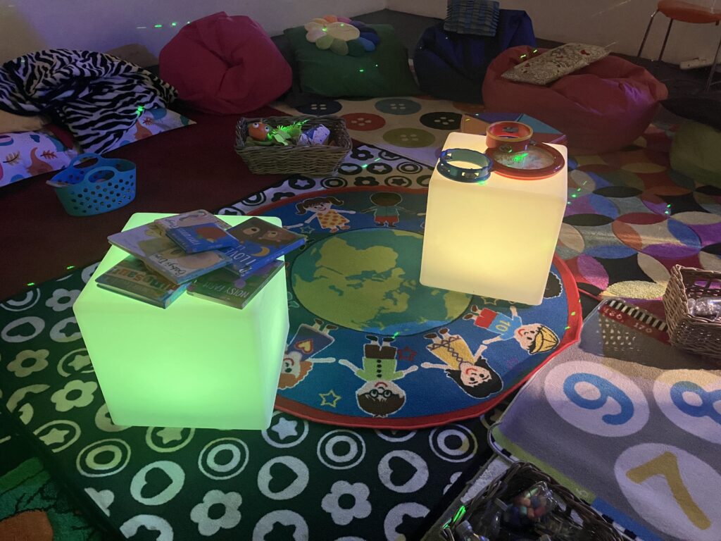 Glowing cubes in a dark room surrounded by books, musical instruments and toys.