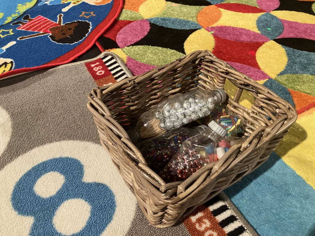 Musical toys in a basket sitting on a colourful, soft carpet