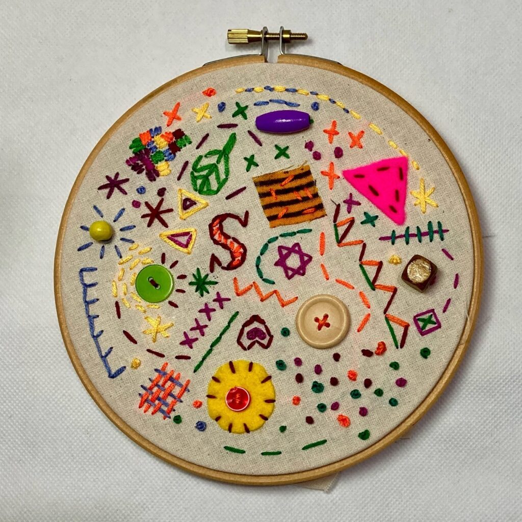 An embroidery hoop decorated with colourful stitched designs