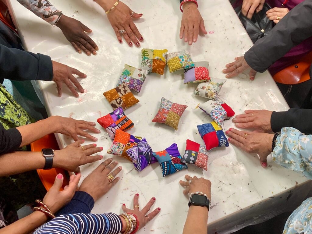 A circle of hands show off mini cushions 